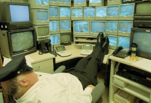 Security Guard Sleeping at Monitors --- Image by © Phil Banko/CORBIS