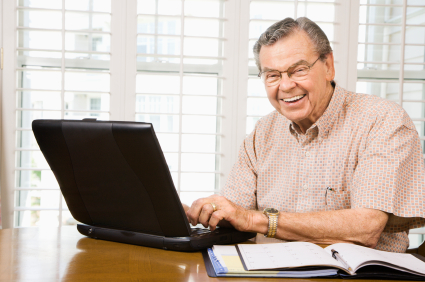 Mature Caucasian man typing on laptop in home.
